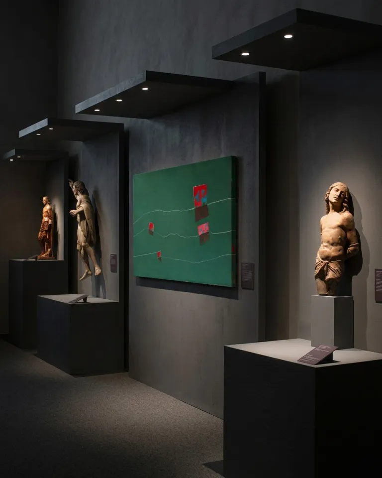 The emerald green canvas NEXUS by Maurizio Valch exhibited alongside medieval polychrome wood sculptures under directed lighting.