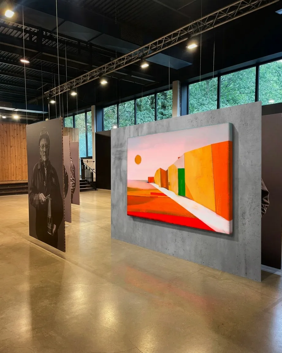 VIA SOLIS by Maurizio Valch installed on a concrete panel in an industrial gallery space, alongside large suspended monochrome portraits of workers.