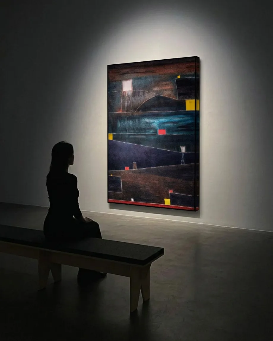 Una visitante sentada observa ADITUS de Maurizio Valch, pintura abstracta vertical con veladuras claras, franjas oscuras, banda turquesa y pequeños acentos rojos y amarillos.