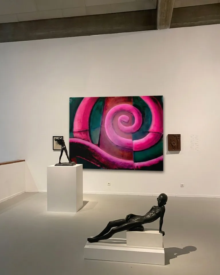 El cuadro VORAGO colgado en una sala blanca de museo, flanqueado por esculturas figurativas de bronce sobre pedestales.