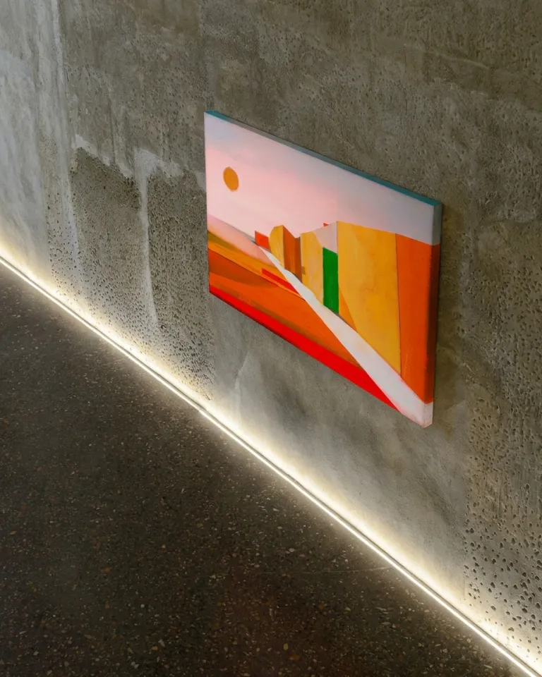 VIA SOLIS by Maurizio Valch, an abstract painting in red, orange, and yellow tones with a white path, installed on a textured concrete wall.