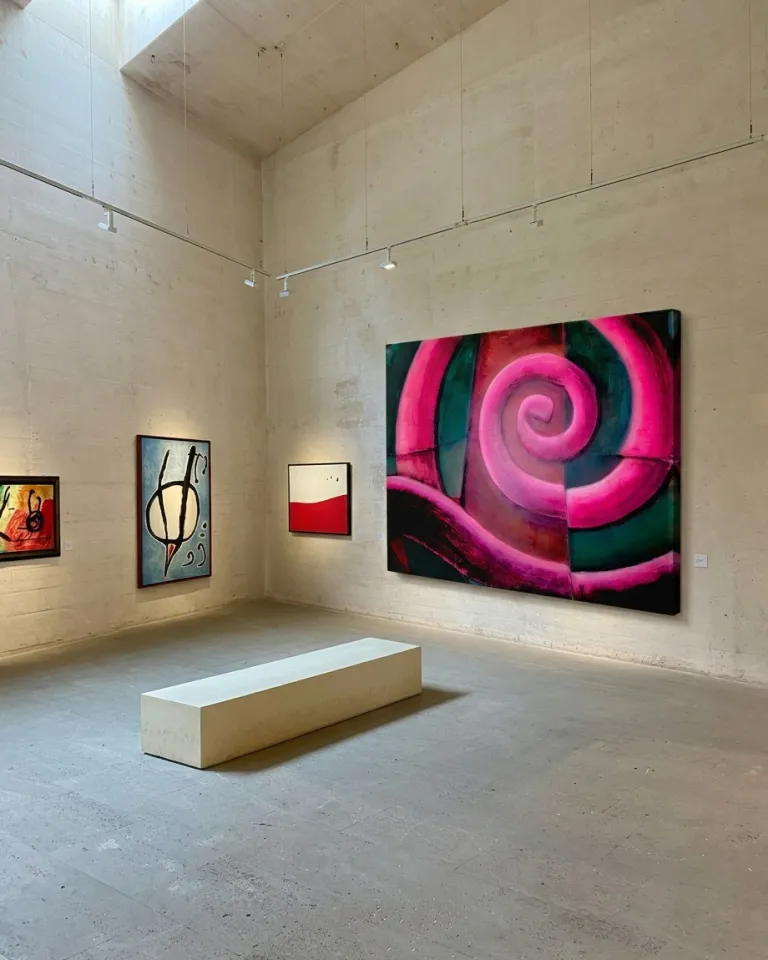 Pintura abstracta de gran formato con una densa espiral fucsia sobre fondo oscuro, expuesta en una sala de galería de estilo industrial con paredes de hormigón y un banco central.