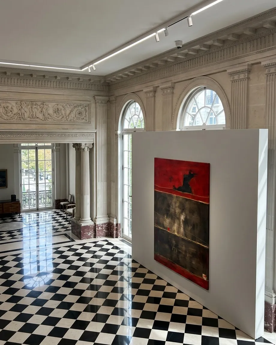 El cuadro abstracto 'Un solo paso en la ceniza' de Maurizio Valch expuesto sobre un tabique blanco en una gran sala de estilo clásico con suelo de baldosas blancas y negras en damero.