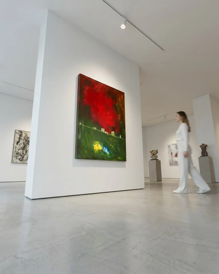 Exhibition display of the vertical abstract painting 'A Theory of Light and Shadows' by Maurizio Valch on a white gallery wall, featuring a female viewer dressed in white walking in the foreground.