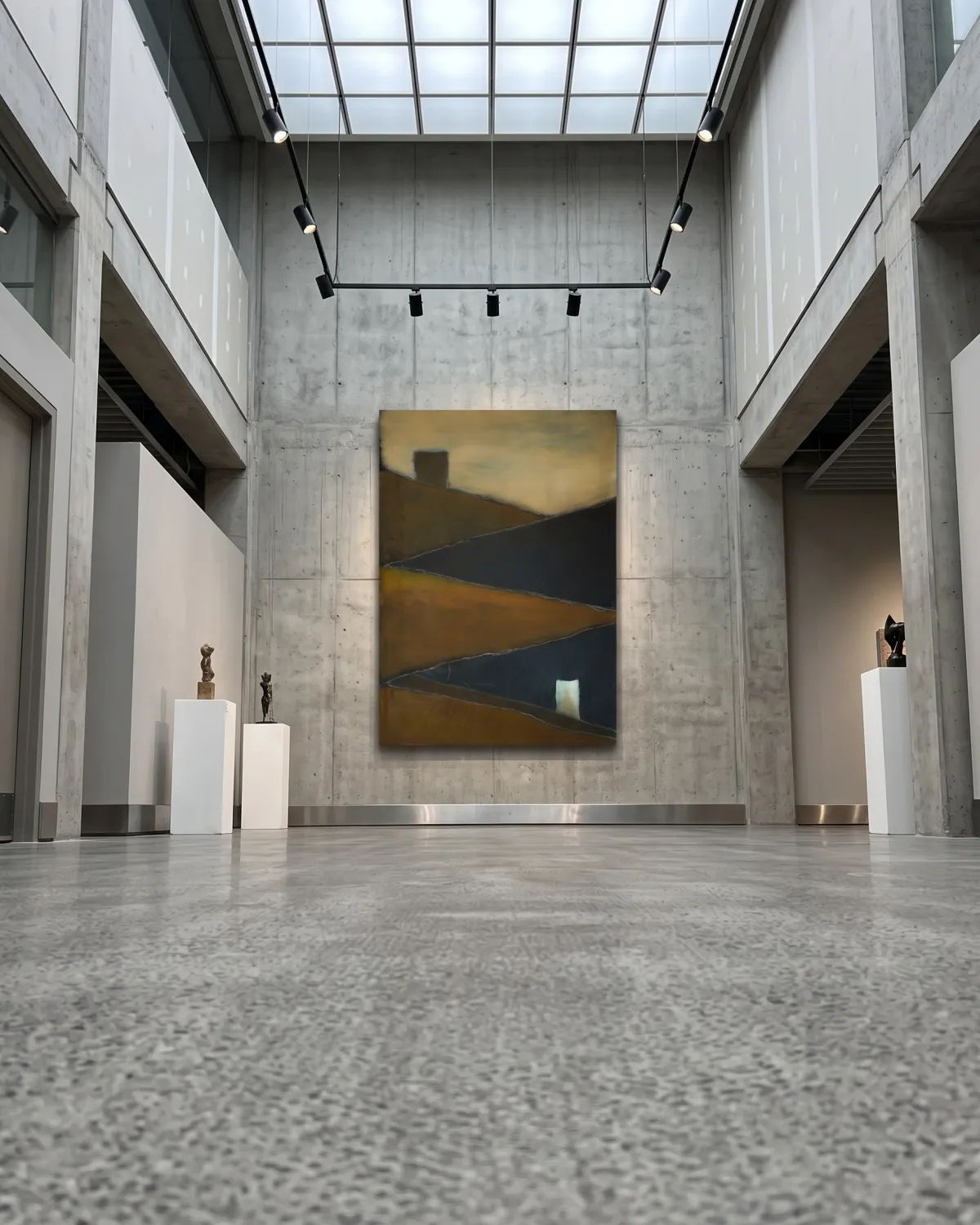 Gran pintura abstracta de Maurizio Valch centrada en una pared de hormigón en una sala de exposición de estilo brutalista bajo un tragaluz de rejilla.